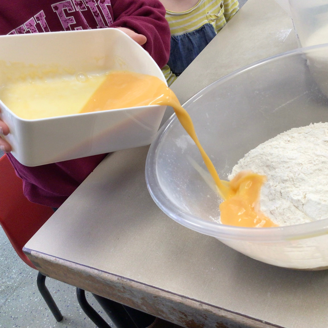 pouring egg into flour to make pancakes